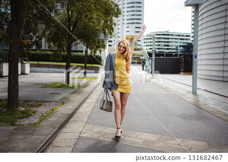 Confident woman celebrating success walking in city street 131682467