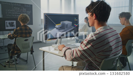 Young Man with Dark Hair Concentrates on 3D House Design at Computer in Classroom 131682580