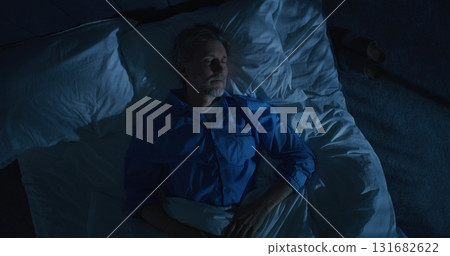 Gray Haired Mature Man Lies in Bed Unable Sleep, Lost in Thoughts About Aging and Solitude Gray Haired Mature Man Lies in Bed Unable Sleep, Lost in Thoughts About Aging and Solitude 131682622