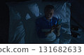 Mature Man Lies in White Bed Under Blanket, Using Smartphone Before Sleep 131682633