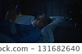 Handsome Gray Haired Man With Beard Laughs and Scrolls Through Social Media at Night 131682640