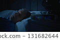 Restless Man in Dark Bedroom, Digital Clock Glowing at Two AM 131682644