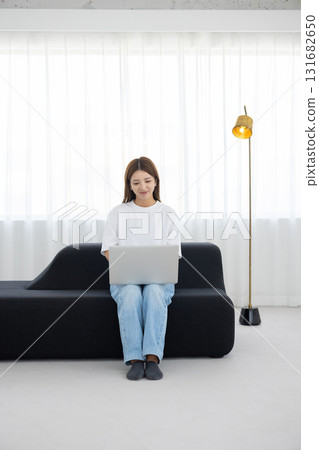 Young woman sitting on sofa and working on computer Young woman sitting on sofa and working on computer 131682650