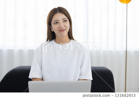 Young woman sitting on sofa and working on computer Young woman sitting on sofa and working on computer 131682653