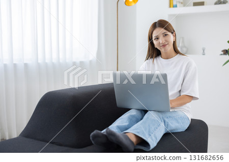 Young woman sitting on sofa and working on computer 131682656