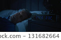 Restless Man in Dark Bedroom, Digital Clock Glowing at Two AM 131682664