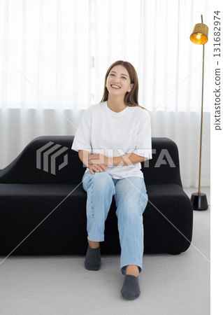 坐在沙發上微笑的年輕女人 131682974