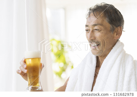 一位 60 多歲的男子手持啤酒杯,面帶微笑 一位 60 多歲的男子手持啤酒杯,面帶微笑 131682978