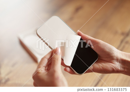 Woman removing protective film from new smartphone 131683375