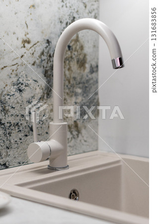 Modern kitchen faucet on a sleek artificial stone sink. 131683856