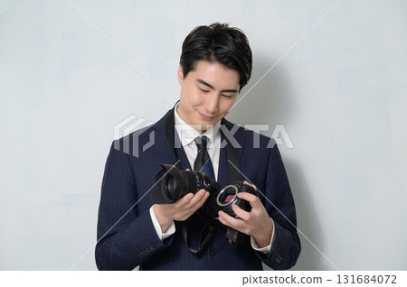 A man in a suit changing a camera lens A man in a suit changing a camera lens 131684072