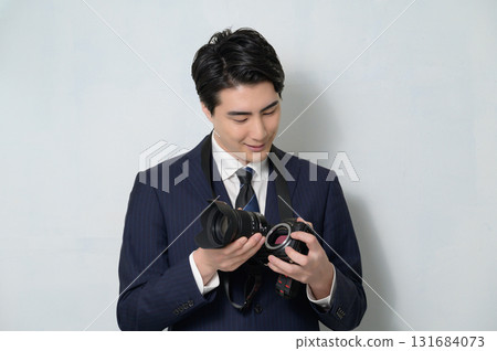 A man in a suit changing a camera lens A man in a suit changing a camera lens 131684073