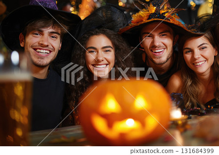 Ai generated friends in witch costumes and hats holding pumpkin celebrating Halloween party at home. 131684399