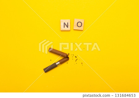 Top view of broken cigarette with the word no on a yellow background closeup 131684653