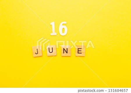 Top view of word 16 June calendar date made by wooden cubes on yellow color background 131684657