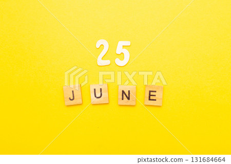 Top view of word 25 June calendar date made by wooden cubes on yellow color background Top view of word 25 June calendar date made by wooden cubes on yellow color background 131684664