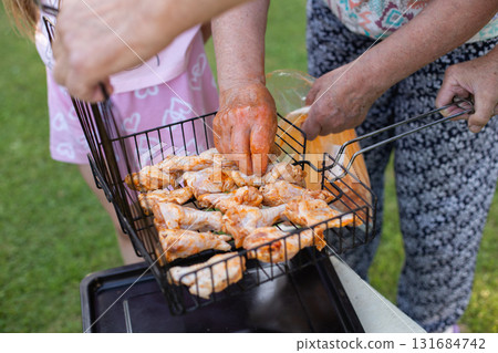 Happy family preparing barbecue in the garden together outdoor. 131684742