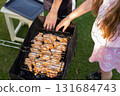 Kida grilling chicken on a barbecue grill in a backyard during summer holidays. 131684743