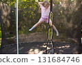 Child girl jumping on trampoline outdoors in the yard on summer vacation. 131684746
