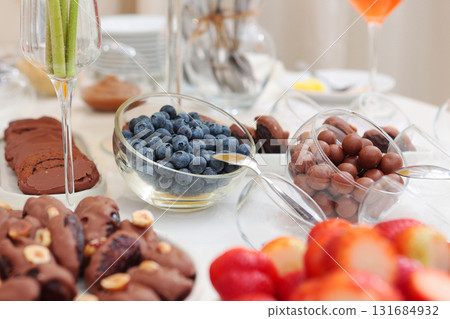 Snacks on holiday. Blueberries, raspberries and strawberries on table. Variety of chocolate desserts.Off-site party service. 131684932