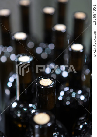 Bottles of wine without labels. Young wine in bottles without labels. Craft winery. A large number of bottles of wine. Selective focus. 131684951