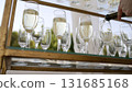 A bottle of sparkling champagne and glasses are poured into a glass at an outdoor wedding event. Open catering, champagne is poured into a glass, close-up. The waiter pours champagne into a glass. 131685168