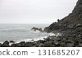 Rocky coastline meeting the ocean under cloudy sky 131685207