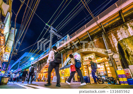 Tokyo cityscape, Japan, October 2nd. View of Shimbashi Station's Karasumori Exit (back of the screen), the bar district under the elevated tracks, and trains on the Keihin-Tohoku Line. 131685562