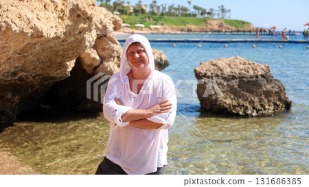 Tourist Man on Egyptian Beach Wearing a White Tunic and Hooded Cover to Beat the Heat, Enjoying the Sun and Sea in a Tropical Paradise 131686385