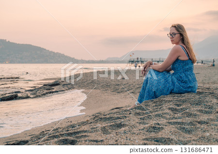 Woman sits on the beach and looks at the sea in Alanya city 131686471