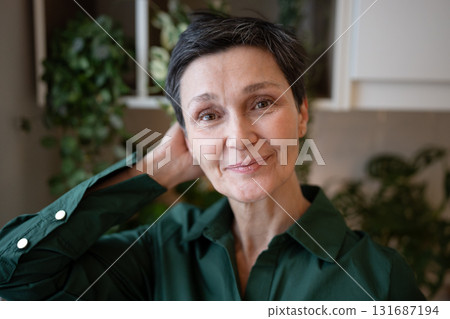 Smiling mature woman looking at camera, smoothing hair. Confident female portrait, happy senior 131687194