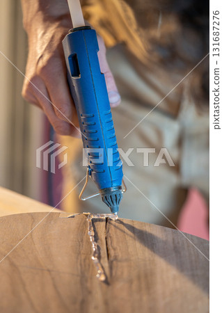 Tracing crack edges with silicone on wooden item before filling with epoxy resin to prevent spread Tracing crack edges with silicone on wooden item before filling with epoxy resin to prevent spread 131687276