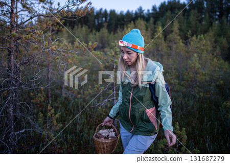 Focused woman with headlamp foraging mushrooms in cold autumn forest at twilight, North solo travel 131687279
