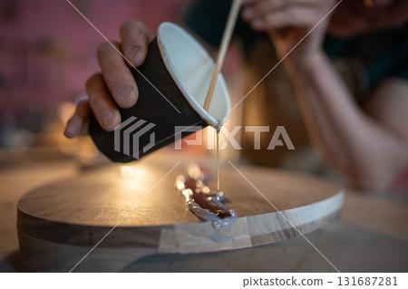 Craftsman pouring epoxy resin into crack on wood surface using stick within silicone formed borders Craftsman pouring epoxy resin into crack on wood surface using stick within silicone formed borders 131687281