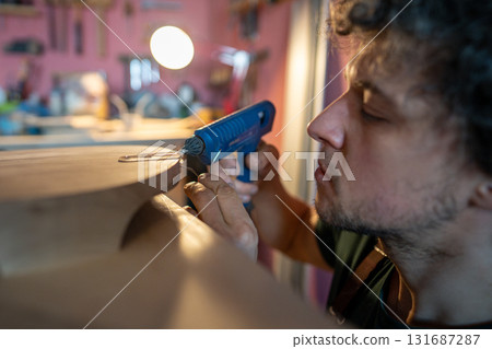 Woodworker apply hot silicone in cracks on wooden object to seal edges before epoxy resin injection 131687287