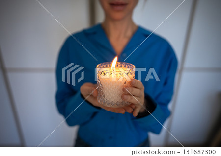 Woman holding scented candle with essential oils for stress relief meditation. Self care routine. Woman holding scented candle with essential oils for stress relief meditation. Self care routine. 131687300