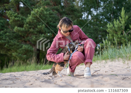 Frightened cat climbs onto woman hands during beach walk. Owner hugs comforts stressed feline Frightened cat climbs onto woman hands during beach walk. Owner hugs comforts stressed feline 131687309