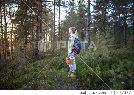 Female backpacker looking into distance breathing fresh forest air after mushroom foraging 131687327