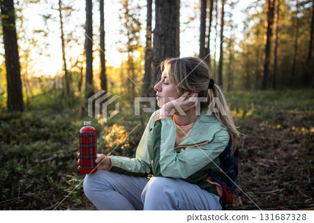 Blissful female tourist listen forest sounds drink hot tea in woodland. Quiet reflection meditation 131687328