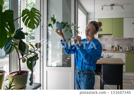 Serious woman with Philodendron in hand, closely inspect leaves and stems, check plant healthcare 131687340