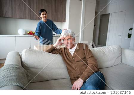 Tired husband sit indifferent on sofa ignoring raging angry meticulous wife shouting blaming 131687346