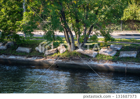 Granite embankment restoration on riverbank with replacement of stone slabs to stabilize shoreline Granite embankment restoration on riverbank with replacement of stone slabs to stabilize shoreline 131687373