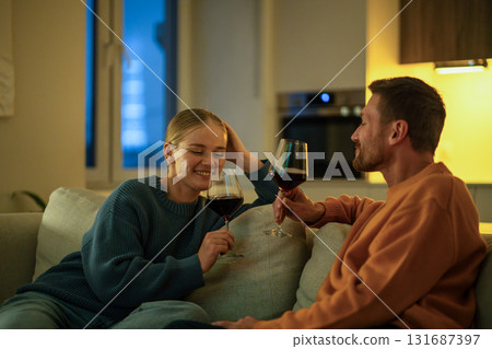Glad romantic couple drinking wine from glasses on evening date at home on sofa, intimate bonding 131687397