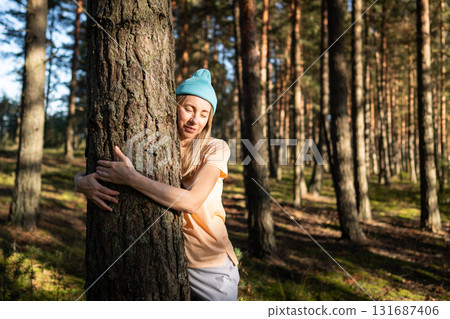 Loving nature purity. Relaxed woman hugging tree trunk in autumn forest at sunset. Stress relief Loving nature purity. Relaxed woman hugging tree trunk in autumn forest at sunset. Stress relief 131687406