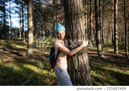 Loving nature purity. Relaxed woman hugging tree trunk in autumn forest with closed eyes at sunset. 131687409