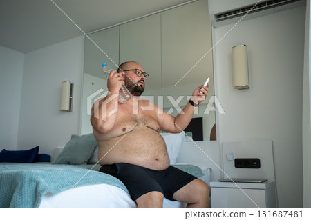 Overweight man sweats adjusts air conditioner to cope with abnormal degrees suffers dying from heat. Overweight man sweats adjusts air conditioner to cope with abnormal degrees suffers dying from heat. 131687481