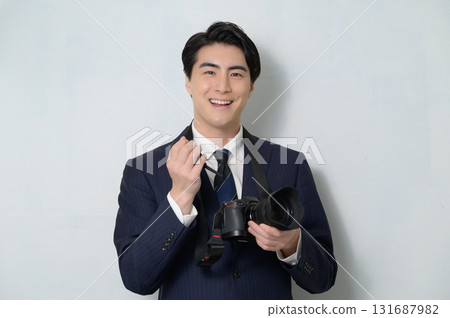 Japanese man in a suit taking care of his camera 131687982