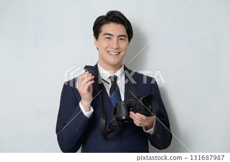 Japanese man in a suit taking care of his camera Japanese man in a suit taking care of his camera 131687987