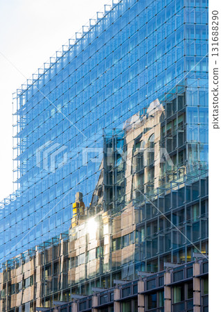 The old structure is mirrored in the glass facade of a modern building in London. This scene captures the blend of history and contemporary design along the Thames River. 131688290