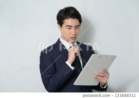 A worried man in a suit holding a clipboard A worried man in a suit holding a clipboard 131688312